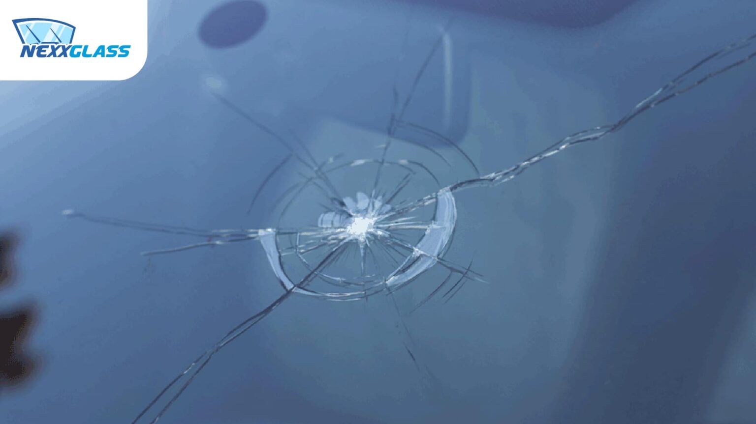 Impact en étoile et fissures sur un pare-brise de voiture avant réparation par Nexxglass